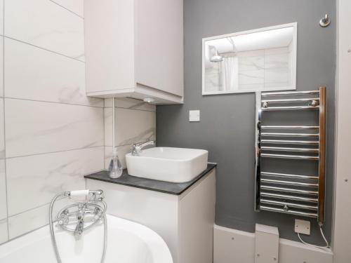 a white bathroom with a sink and a mirror at Jessie's Cottage in Kendal