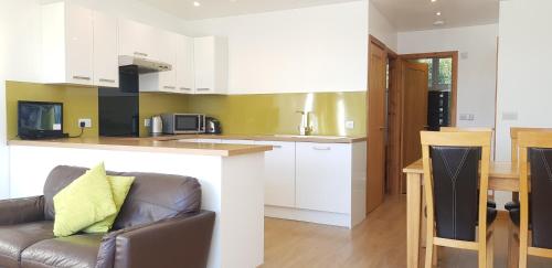 a kitchen and living room with a couch and a table at Marina Boathouse, lake windermere lets in Bowness-on-Windermere