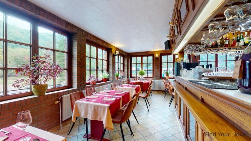 un restaurante con mesas y sillas en una habitación con ventanas en Hotel IL Castellino, en Chaudfontaine