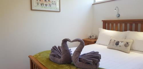 two towel swans sitting on top of a bed at Marina Boathouse, lake windermere lets in Bowness-on-Windermere