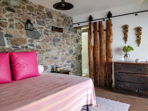 a bedroom with a bed and a stone wall at Calhau Grande in Arco da Calheta