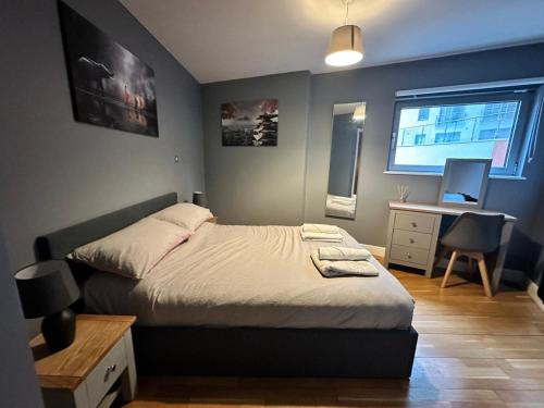 a bedroom with a bed and a desk and a window at Fantastic and modern city centre flat with FREE parking! in Cardiff