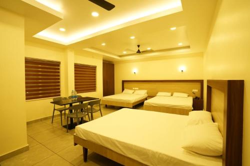 ein Hotelzimmer mit 2 Betten und einem Tisch in der Unterkunft SREENARAYANA TOURIST HOME in Guruvāyūr