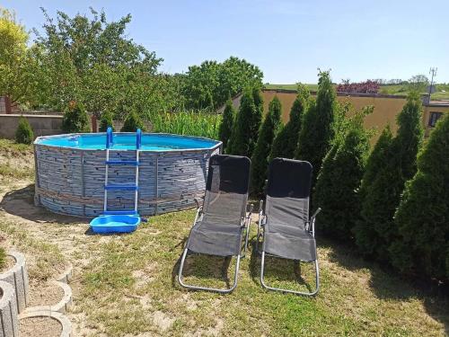 two chairs and a pool in a yard at Apartmán Vendelínka in Valtice