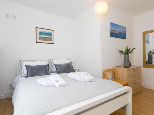 a bedroom with a white bed with two pillows at 5 St Brigids in St Ives