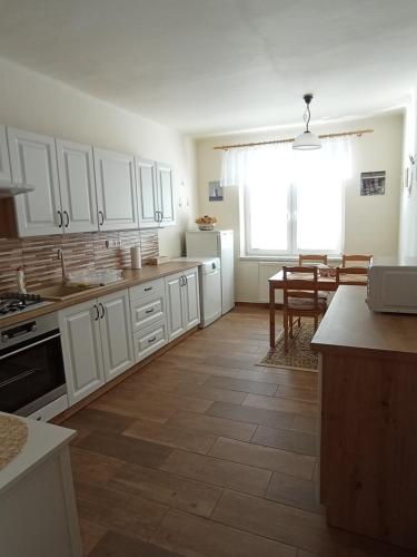 a kitchen with white cabinets and a wooden floor at Apartment Krnov in Krnov