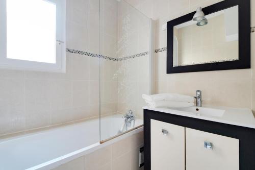 une salle de bain avec un lavabo, une baignoire et un miroir dans l'établissement CHAMPS DE MARS - GRENELLE, à Paris