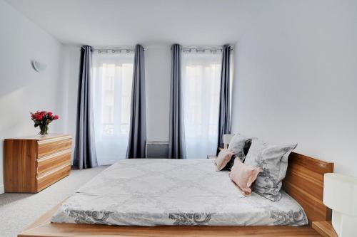 - une chambre avec un lit, une commode et des fenêtres dans l'établissement CHAMPS DE MARS - GRENELLE, à Paris