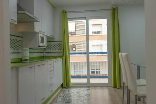 una cucina con mobili bianchi e una grande finestra di 085 - Gaviotas 005 - comfortHOLIDAYS a Santa Pola