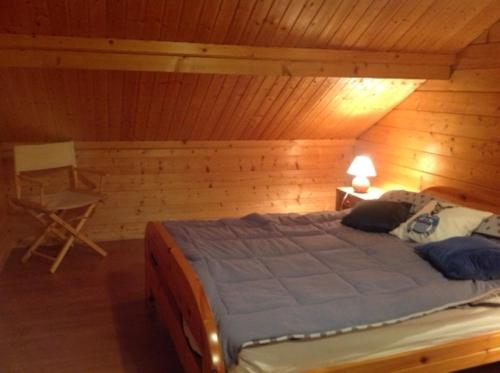 um quarto com uma cama grande num quarto de madeira em chalet de la haute fontaine em Anould