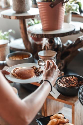 une personne mangeant de la nourriture sur une table avec une assiette de nourriture dans l'établissement L'Ermitage Hôtel Cuisine-À-Manger, à Saint-Cyr-au-Mont-dʼOr