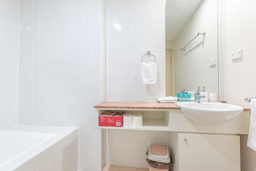 a white bathroom with a sink and a tub at Cozy 2BD Apt w Waterview near Olympic Park in Sydney