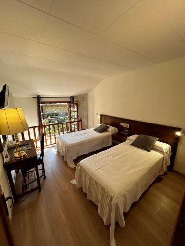a hotel room with two beds and a window at Hotel Santa Bàrbara De La Vall D'ordino in Ordino