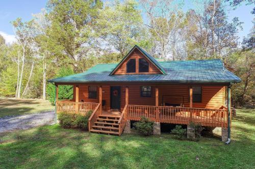 eine Hütte im Wald mit einer großen Terrasse in der Unterkunft Rivendell Creekside Cabin in Cosby