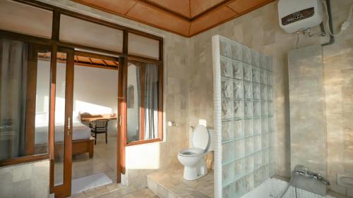 a bathroom with a toilet and a tub and a sink at New Mumbul Ubud in Ubud