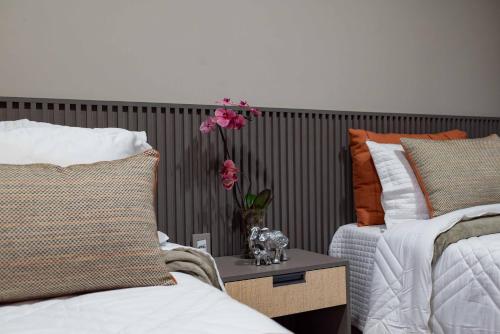 a bedroom with two beds and a vase with flowers on a table at Spa Agua Milagrosa in Cuiabá