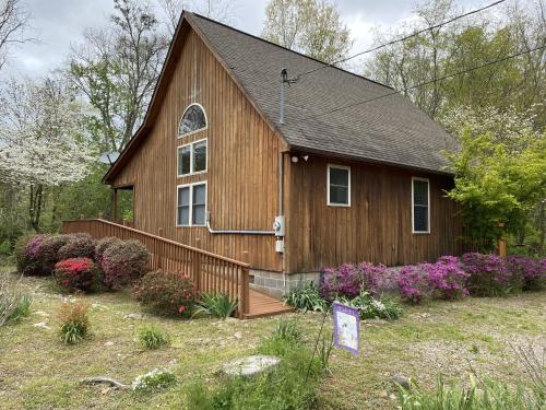 una piccola casa in legno con dei fiori di fronte di Gray's Place on Cosby Creek - 2 Bedrooms, 2 Baths, Sleeps 6 home a Cosby