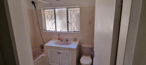 a bathroom with a sink and a toilet and a mirror at Cottage on Kei in Germiston