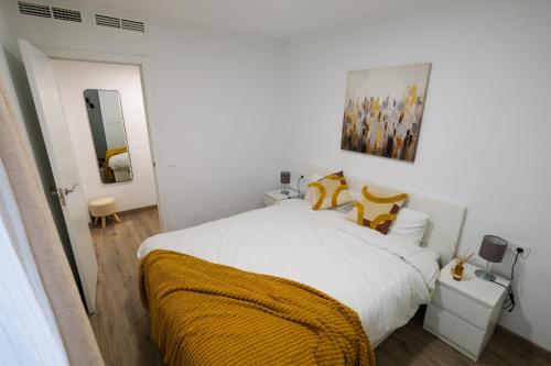 um quarto branco com uma cama grande e almofadas amarelas em 2B PlusUltra piso de 1 dorm em Alicante