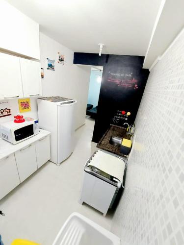 a kitchen with white cabinets and a black wall at Ap frente para o mar in Caraguatatuba