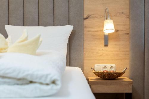 a bed with a clock and a bowl of fruit on a night stand at Appartement Krippenstein mit Indoorpool und Sauna in Bad Goisern