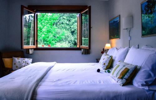 a bedroom with a large white bed with a window at Hotel Las Cascadas in La Cumbrecita