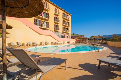 a swimming pool with chairs and a building at Hotel La Baja in Santa Caterina