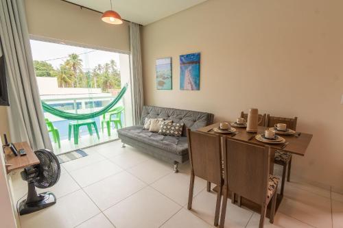 uma sala de estar com uma mesa e um sofá em Flats Mar'Bella A melhor Localização com Varanda, Cozinha, Estacionamento e Home Office a 100M praia Barra Grande/Maragogi em Maragogi
