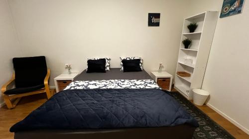 1 dormitorio con 1 cama con edredón negro y silla en Cozy Home Stay in Kungsängen-Read Host info, en Estocolmo