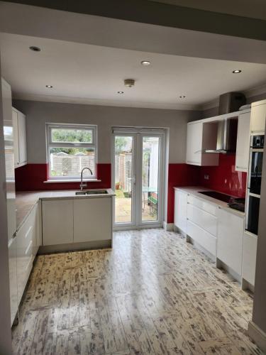 a large kitchen with white cabinets and red walls at Chi Lodge & Accommodation in Rainham