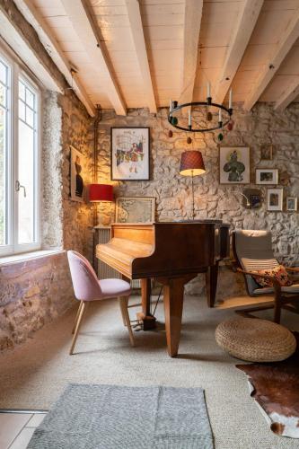 a living room with a piano and a stone wall at Grande Maison Creuzier - Villa 3 chambres et jardin in Creuzier-le-Neuf