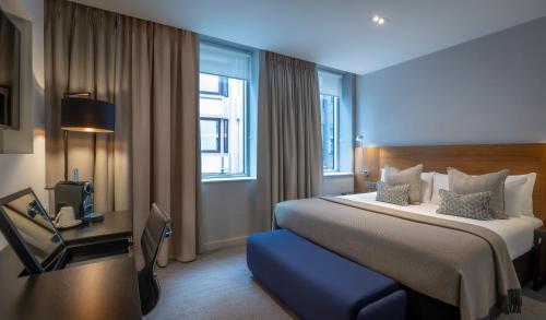 a hotel room with a large bed and a desk at Clayton Hotel London Wall in London