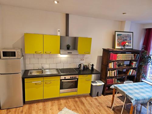 La cuisine est équipée de placards jaunes, d'un évier et d'un réfrigérateur. dans l'établissement Cosy apt à 200m de la Cathédrale, à Liège