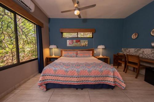 a bedroom with a bed with blue walls and windows at Xalli Beach Hotel in Altagracia