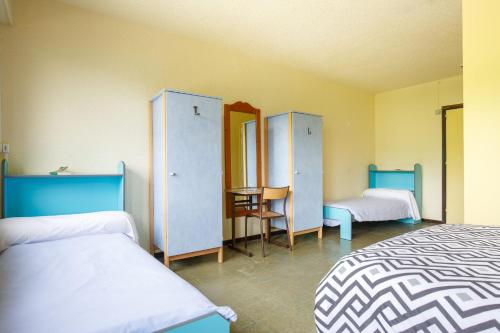 a room with two beds and two wardrobes at Auberge de jeunesse HI Valmeinier in Valmeinier