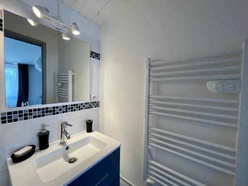 a white bathroom with a sink and a mirror at Charmante maison / Proche du lac de Casteljaloux in Casteljaloux