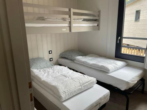 deux lits assis dans une pièce avec une fenêtre dans l'établissement Cottage dans Parc Résidentiel de Loisirs, Piscine, 150M de la mer, à Jullouville