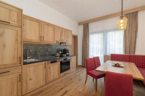 a kitchen with wooden cabinets and a table with red chairs at Appartementhaus Dachsteinblick in Bad Goisern