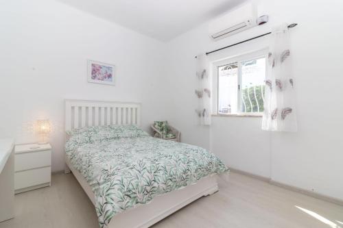 a white bedroom with a bed and a window at Casa Pachorrenta in Carvoeiro