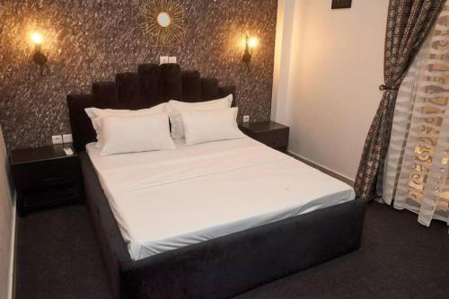 a bedroom with a large bed with white sheets and pillows at appartement cosy free bonapriso in Douala