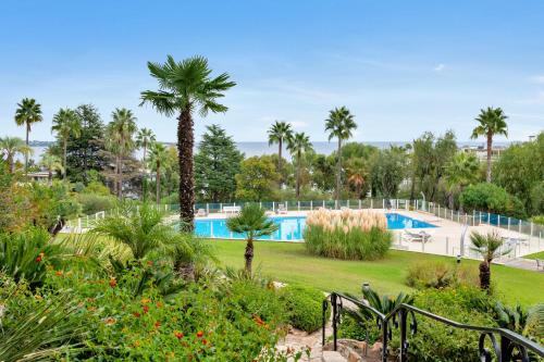 a resort with a swimming pool and palm trees at Le Mirandole : Piscine et Tennis Résidence luxe in Vallauris