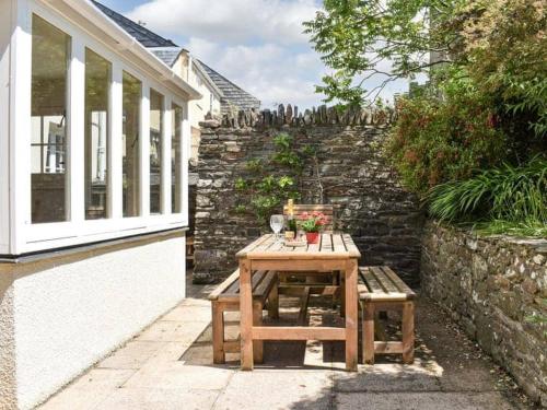 a wooden table and two chairs next to a stone wall at The Glen at Ugborough - South Hams Holiday Home in Ugborough