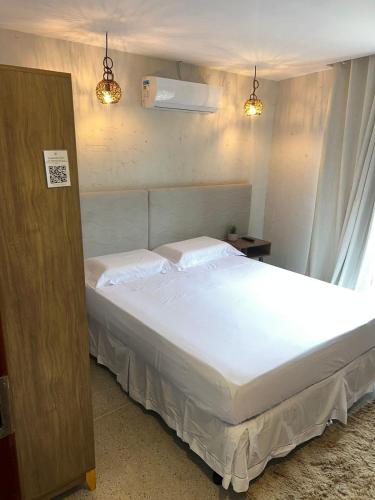 a bedroom with a bed with white sheets and two lights at NOAH Rústico Hotel in Bôca da Mata