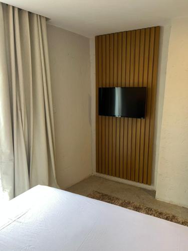 a bedroom with a television on a wall with a curtain at NOAH Rústico Hotel in Bôca da Mata