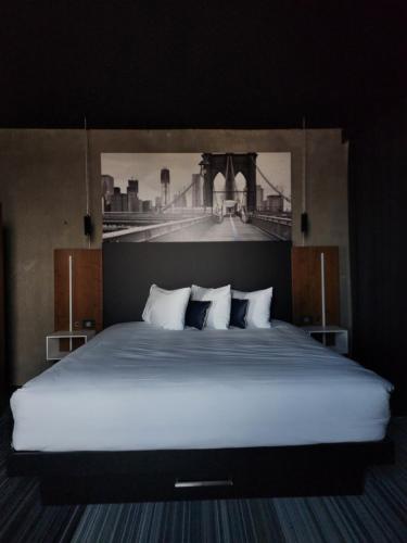 Un dormitorio con una cama grande con una foto de un puente en Grand Times Hotel Laval - Centropolis en Laval