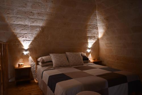 um quarto com uma cama numa parede de tijolos em Faliero Room em Canosa di Puglia