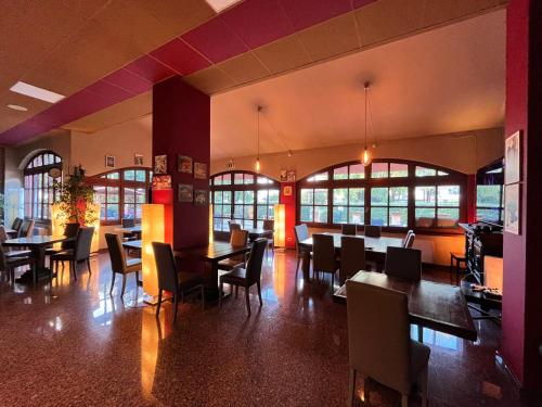 un comedor con mesas, sillas y ventanas en Hotel Erbaluce, en Caluso