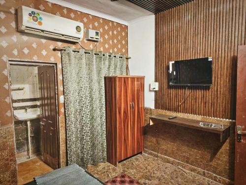 - un salon avec une télévision et un rideau dans l'établissement Metroview rooms & hotel, à Bahādurgarh