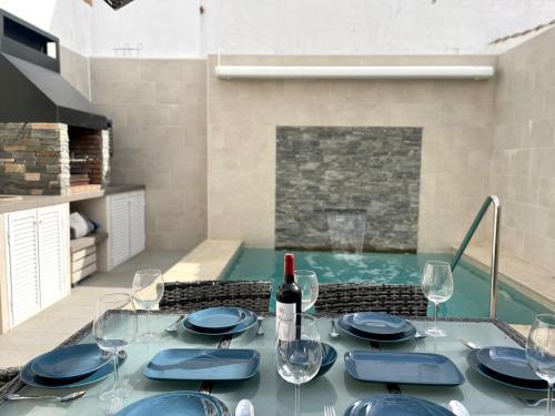 una mesa de comedor con una botella de vino y copas en Casa El Patio, en Chiclana de la Frontera