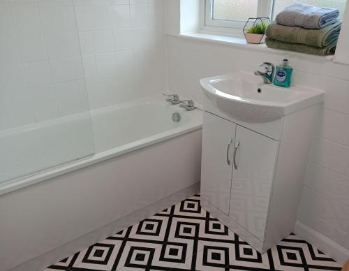 y baño blanco con lavabo, bañera y lavamanos. en 3BR House with garden near Bicester Village, en Bicester